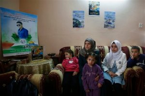 This photograph made on Wednesday, Oct. 28, 2015, shows family of a 16-year-old Palestinian Tareq Natshe, who stabbed and wounded a soldier Oct. 17, before being shot dead. sit underneath posters depicting him at their home in Hebron, West Bank. The West Bank's largest city has become a focal point in Israeli-Palestinian violence, with near-daily deadly confrontations erupting at Israeli army checkpoints that guard enclaves of ultra-nationalist Jewish settlers in the once thriving center of Hebron. (AP Photo/Nasser Shiyoukhi)