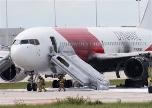 Firefighters walk past a Dynamic Airways Boeing 767, Thursday, Oct. 29, 2015, at Fort Lauderdale/Hollywood International Airport in Dania Beach, Fla. The passenger planes' engine caught fire Thursday as it prepared for takeoff, and passengers had to quickly evacuate on the runway using emergency slides, officials said. The plane was headed to Caracas, Venezuela. (AP Photo/Wilfredo Lee)