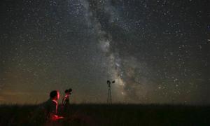 FILE - In this Wednesday, July 23, 2014 file photo, Omaha photographer Lane Hickenbottom photographs the night sky in a pasture near Callaway, Neb. With no moon in the sky, the Milky Way was visible to the naked eye. More than one-third of the world’s population can no longer see the Milky Way because of man-made lights, according to a scientific paper by Light Pollution Science and Technology Institute's Fabio Falchi and his team members, published on Friday, June 10, 2016. (Travis Heying/The Wichita Eagle via AP) LOCAL TELEVISION OUT; MAGS OUT; LOCAL RADIO OUT; LOCAL INTERNET OUT; MANDATORY CREDIT