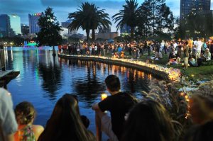People hold candles at a candlelight vigil for the victims of the mass shooting at Pulse nightclub in Orlando, as they gather at Lake Eola Park in Orlando, Fla., Sunday, June 19, 2016. (Craig Rubadoux/Florida Today via AP) MANDATORY CREDIT