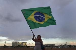 A woman waves a Brazilian flag at a camp, in support of Brazil's suspended President Dilma Rousseff, in Brasilia, Brazil, Sunday, Aug. 28, 2016. Rousseff will face Congress on Monday as her impeachment process enters its final stages. She is accused of using unauthorized loans from state-owned banks and that she illegally issued decrees to make government payments without congressional approval. (AP Photo/Eraldo Peres)
