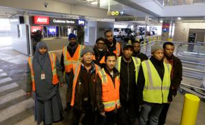 FILE- In this Feb. 17, 2016, file photo, a group of people who work at the rental car facility at Seattle-Tacoma International Airport and are suing their employers over the $15 minimum wage they say they have not been paid, pose for a photo in Seattle, Wash, while on break at their workplace. Two companies that provide baggage and other services at Seattle-Tacoma International Airport have agreed to pay more than $10 million to settle allegations that they ignored the nation's first $15 minimum wage law after it took effect. (AP Photo/Ted S. Warren, file)