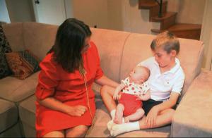 In this frame grab from video, taken Sept. 14, 2016, Sarah Gray with her son Callum, 6, and infant daughter Jocelyn in their Washington home. Callum’s identical twin Thomas died of a birth defect when he was just 6 days old, and the family donated Thomas’ eyes, liver and umbilical cord blood for medical research. Now Gray has written a book about her unusual journey to find out if that donation really made a difference, revealing a side of science laymen seldom glimpse. (AP Photo/Rick Gentilo)